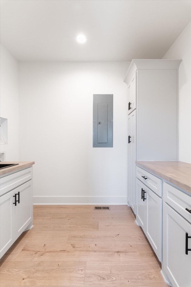 laundry area with baseboards, visible vents, light wood finished floors, electric panel, and recessed lighting