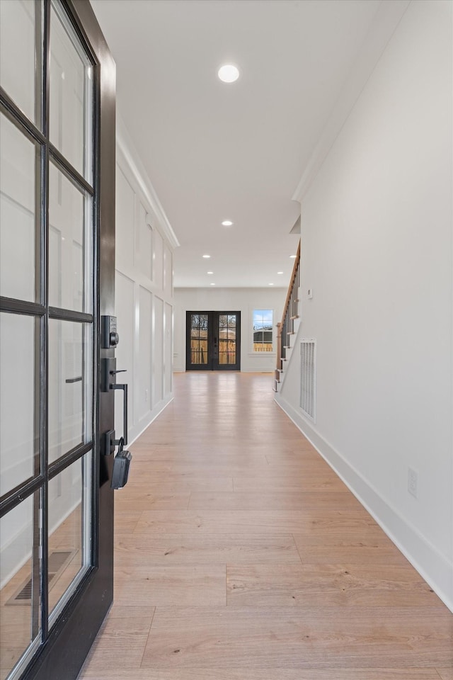 corridor with visible vents, light wood finished floors, baseboards, recessed lighting, and stairs