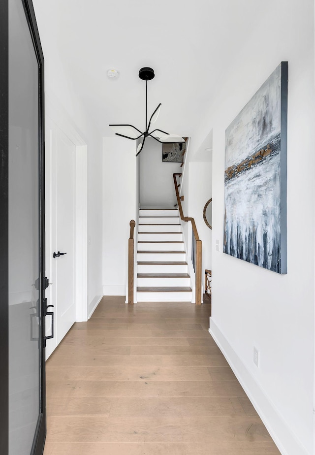 hall with a chandelier and light wood-type flooring