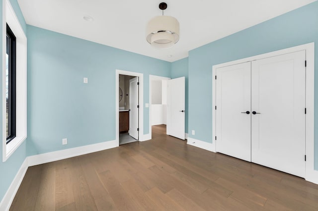 unfurnished bedroom with dark hardwood / wood-style flooring and a closet