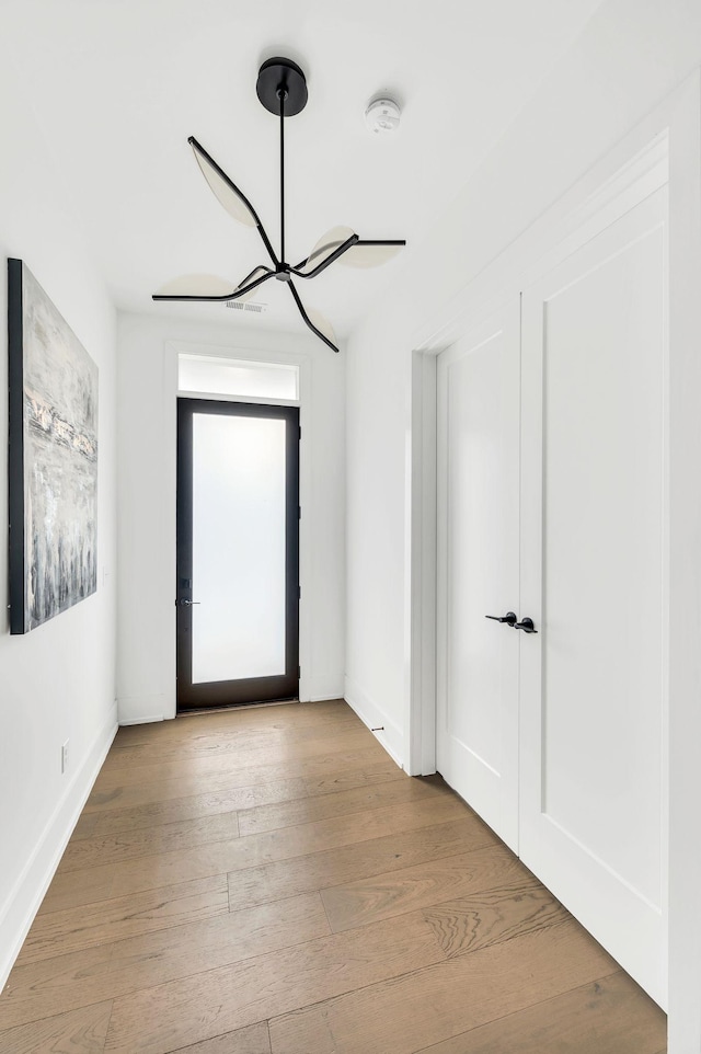 empty room with light hardwood / wood-style flooring and a notable chandelier