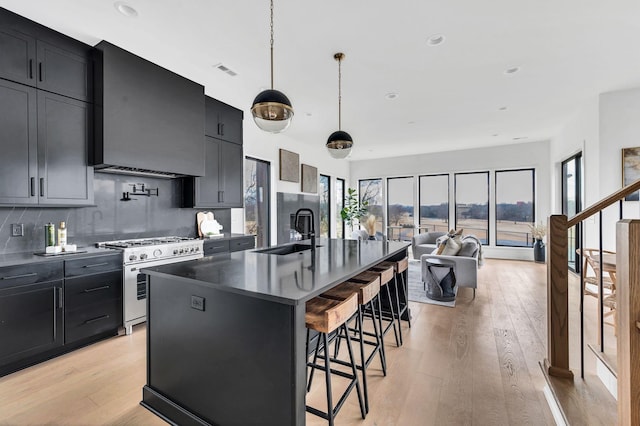 kitchen featuring a kitchen breakfast bar, sink, high end stove, an island with sink, and extractor fan