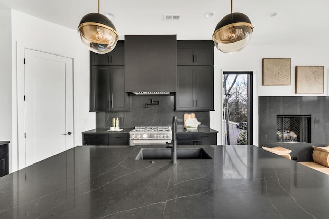 kitchen featuring pendant lighting, backsplash, ventilation hood, sink, and stainless steel range