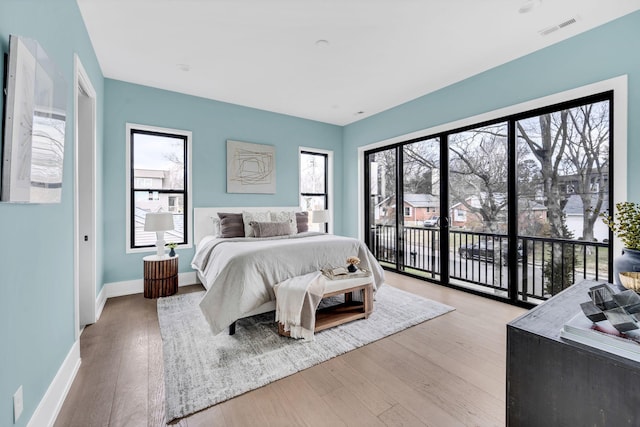 bedroom with light wood-type flooring, access to outside, and multiple windows