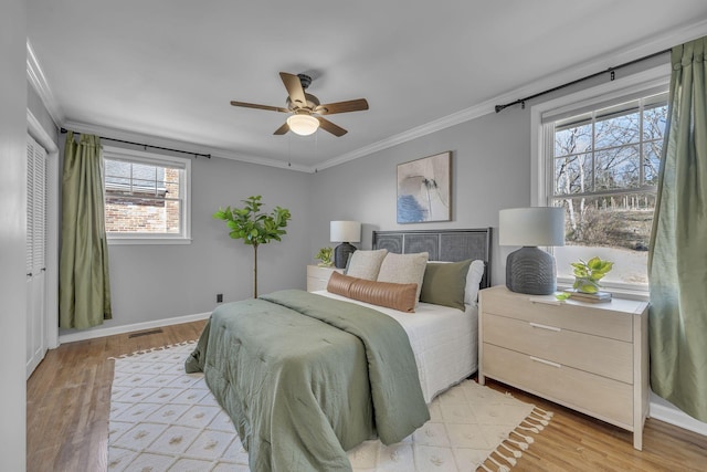 bedroom with crown molding, light wood-type flooring, a closet, and ceiling fan