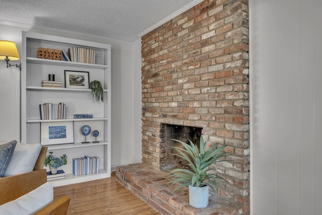 living area featuring a fireplace, hardwood / wood-style flooring, a textured ceiling, and crown molding