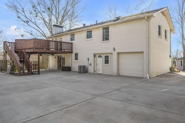 back of property with a garage, a wooden deck, and central AC