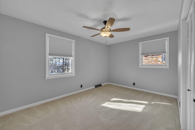 carpeted spare room featuring ceiling fan