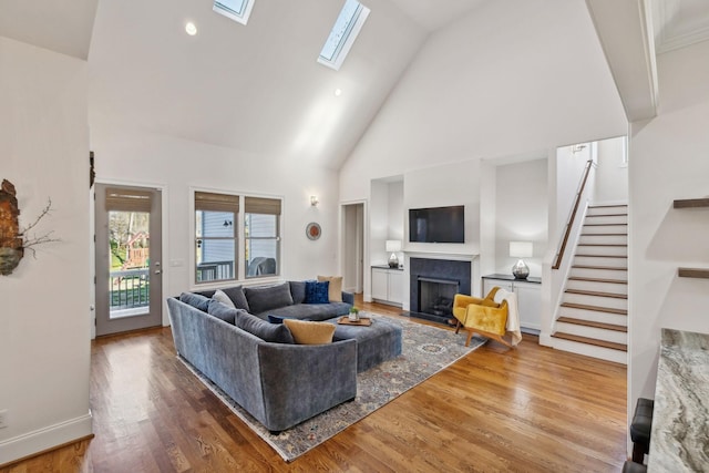 living room with a towering ceiling, a skylight, and hardwood / wood-style floors