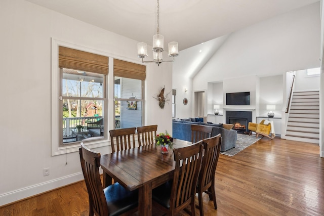 dining area with hardwood / wood-style floors, a notable chandelier, and vaulted ceiling