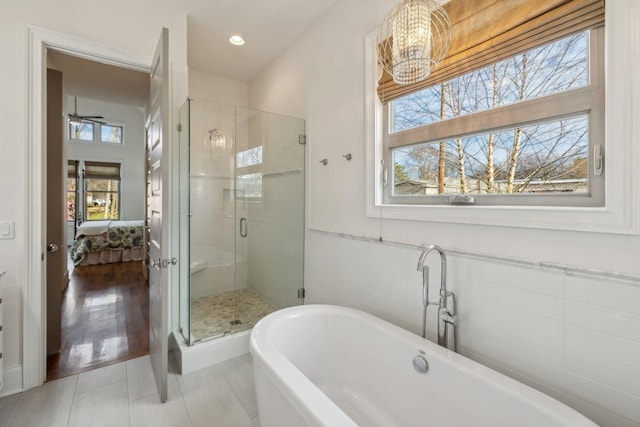 bathroom with tile patterned flooring, plus walk in shower, and ceiling fan with notable chandelier