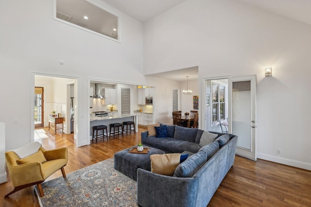 living room with a high ceiling, wood-type flooring, and a notable chandelier