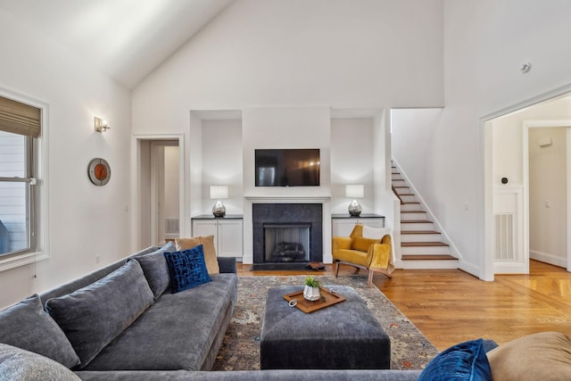 living room featuring a wealth of natural light, high vaulted ceiling, and light wood-type flooring