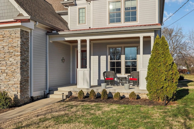 view of exterior entry with a lawn and covered porch