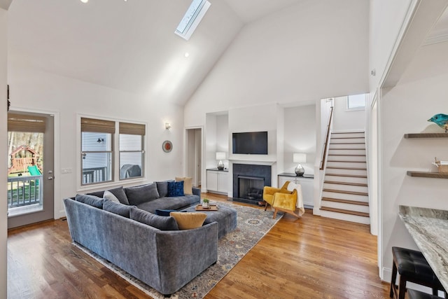 living room featuring hardwood / wood-style floors, a skylight, high vaulted ceiling, and plenty of natural light