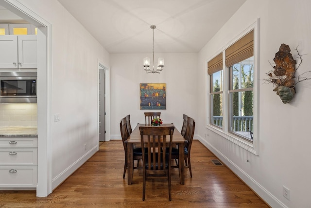 dining space featuring dark wood-type flooring and a chandelier