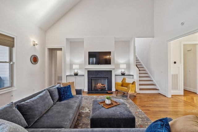 living room with high vaulted ceiling and light wood-type flooring