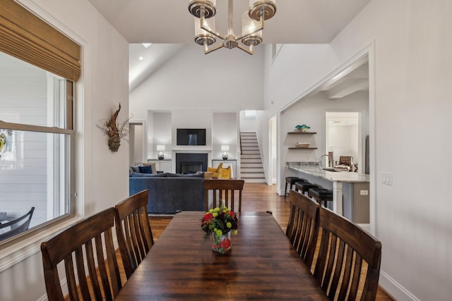 dining area with dark wood-type flooring, lofted ceiling, and a notable chandelier