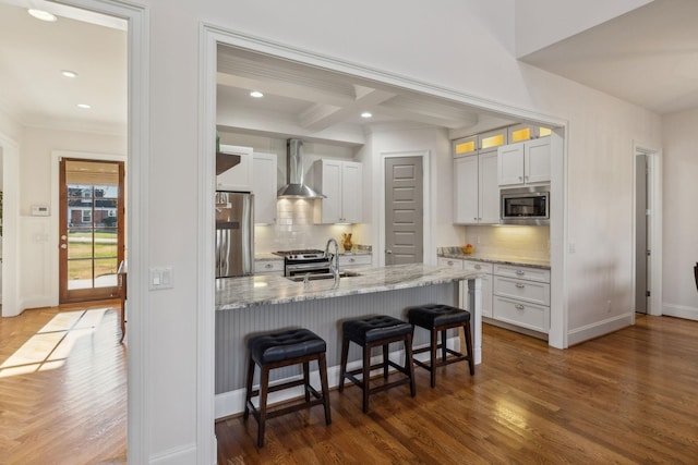 kitchen featuring sink, white cabinets, stainless steel appliances, decorative backsplash, and wall chimney range hood