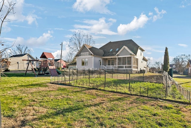 rear view of house featuring a yard, a playground, and a sunroom