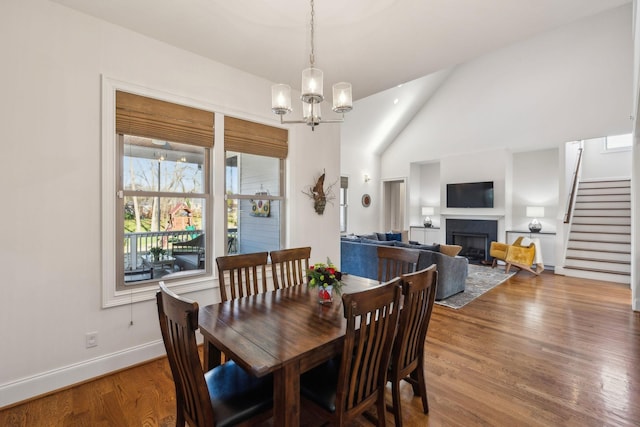 dining space with hardwood / wood-style flooring, lofted ceiling, and an inviting chandelier