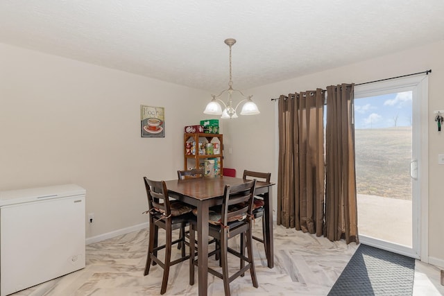 dining area featuring a textured ceiling, baseboards, and a notable chandelier