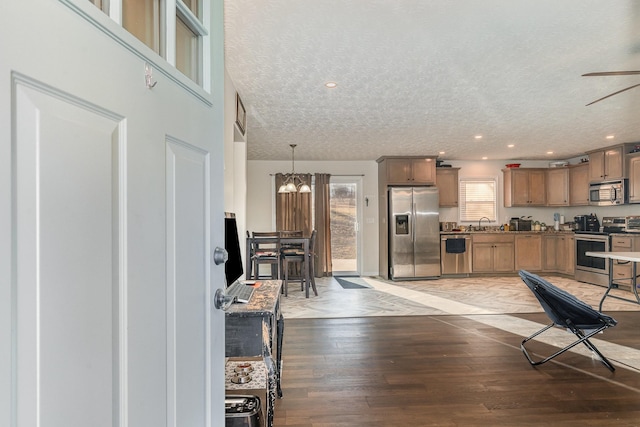 kitchen with a textured ceiling, recessed lighting, a sink, appliances with stainless steel finishes, and light wood-type flooring