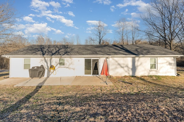 back of house featuring brick siding and a patio