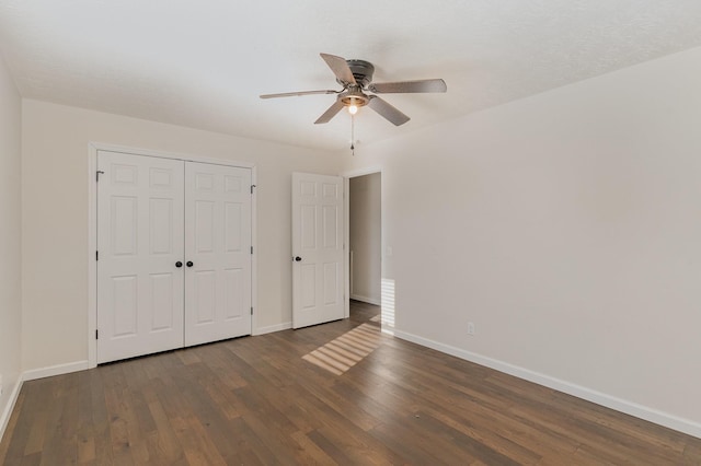 unfurnished bedroom featuring a closet, dark wood-style flooring, baseboards, and a ceiling fan