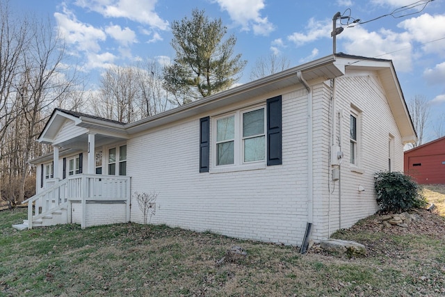 view of side of home featuring covered porch and brick siding