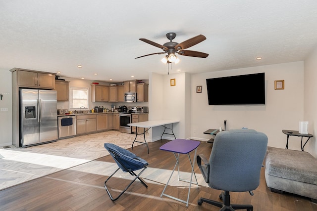 home office featuring light wood-type flooring, a textured ceiling, baseboards, and a sink