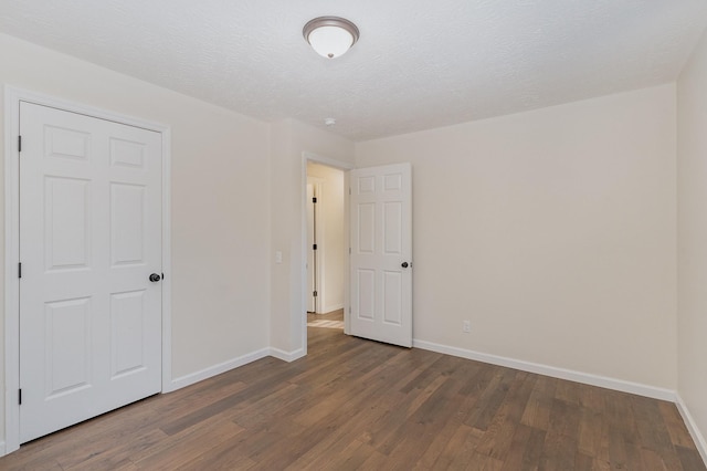 unfurnished bedroom with a textured ceiling, baseboards, and wood finished floors