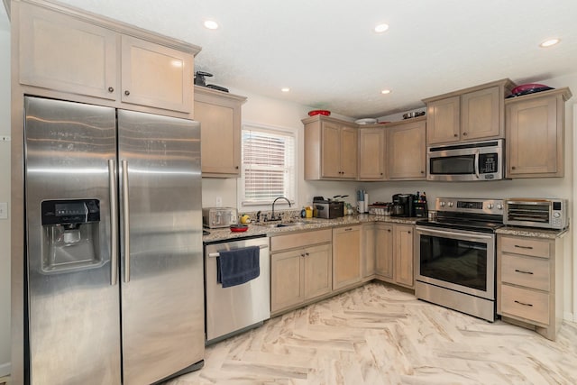 kitchen featuring light stone counters, a toaster, recessed lighting, appliances with stainless steel finishes, and a sink