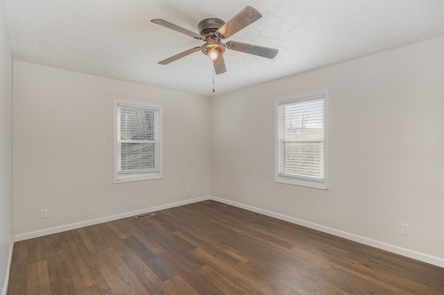 spare room featuring dark wood-style floors, ceiling fan, a textured ceiling, and baseboards