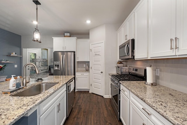 kitchen featuring white cabinetry, sink, stainless steel appliances, dark wood-type flooring, and pendant lighting