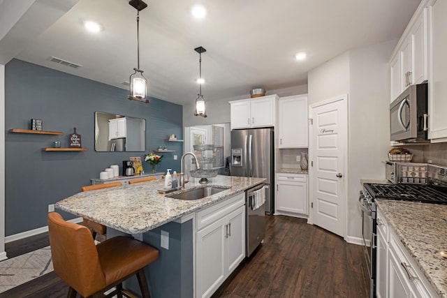 kitchen with white cabinetry, sink, decorative backsplash, a center island with sink, and appliances with stainless steel finishes