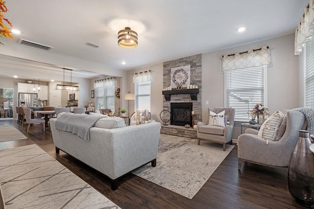 living room with a fireplace, dark hardwood / wood-style flooring, and a chandelier