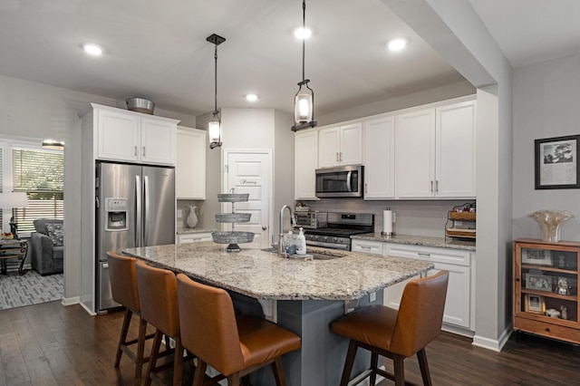 kitchen with white cabinets, stainless steel appliances, and an island with sink