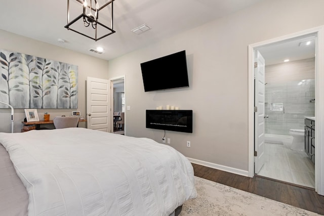 bedroom featuring ensuite bathroom, dark hardwood / wood-style floors, and an inviting chandelier