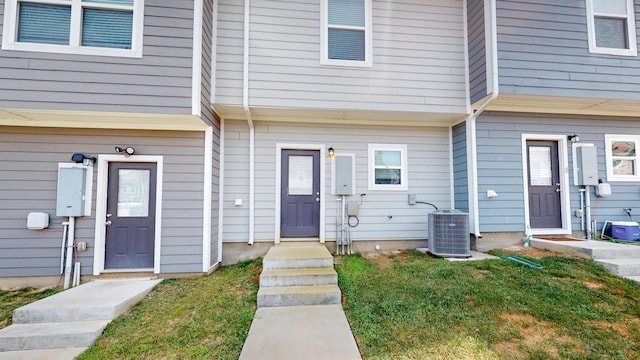 doorway to property featuring a lawn and cooling unit