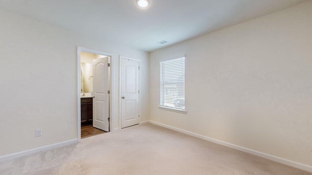 unfurnished bedroom with light colored carpet and ensuite bath