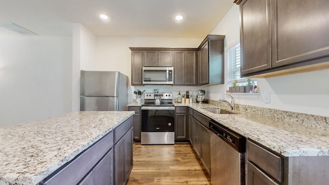 kitchen featuring sink, light hardwood / wood-style flooring, light stone countertops, dark brown cabinets, and stainless steel appliances