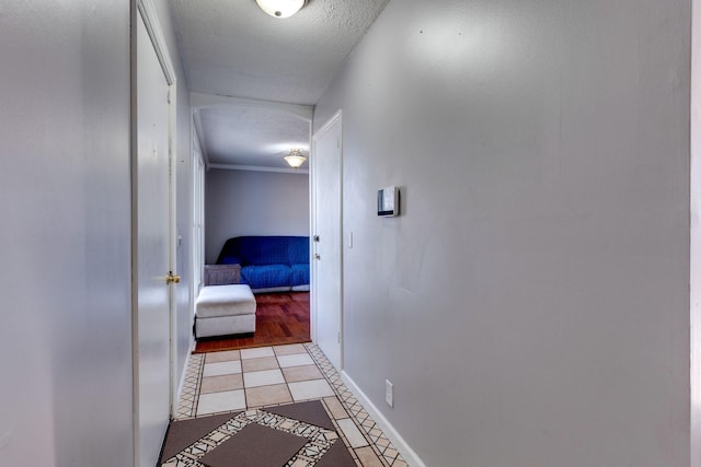 hall with light tile patterned floors, a textured ceiling, and ornamental molding