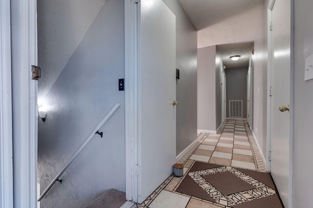 corridor featuring light tile patterned floors and a textured ceiling