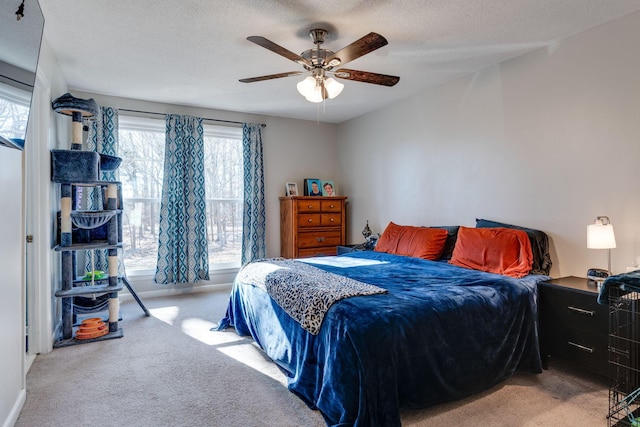 bedroom with ceiling fan, light carpet, and a textured ceiling