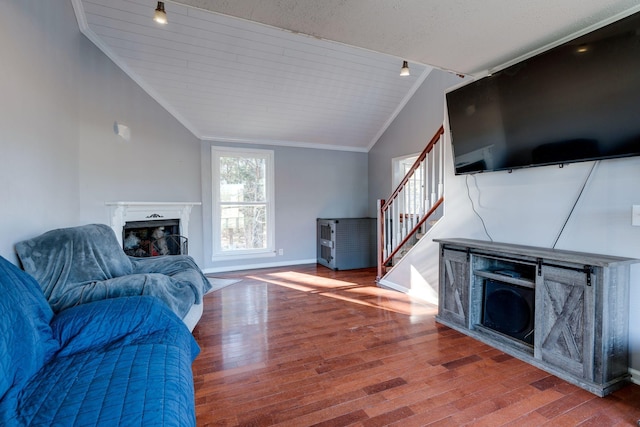 living room featuring hardwood / wood-style floors, vaulted ceiling, and ornamental molding