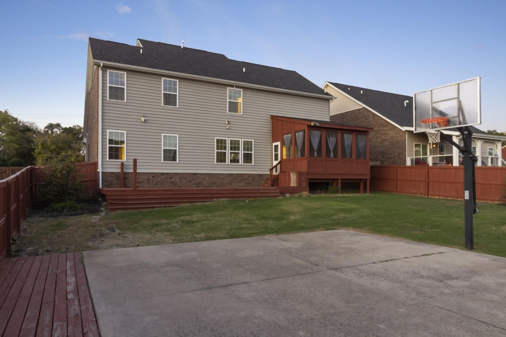 rear view of house featuring a sunroom and a lawn