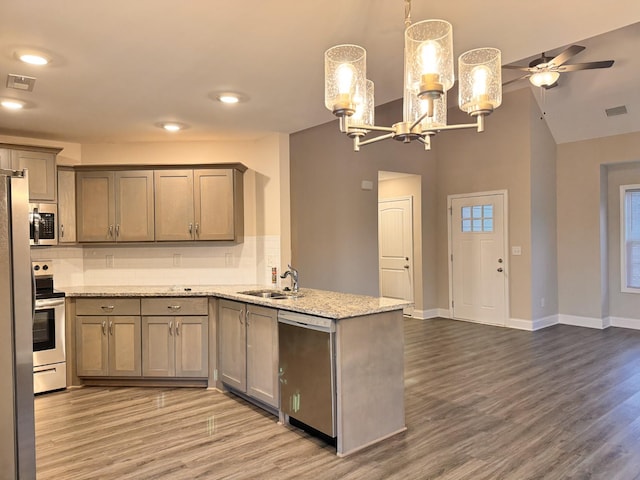 kitchen featuring kitchen peninsula, tasteful backsplash, ceiling fan with notable chandelier, stainless steel appliances, and decorative light fixtures