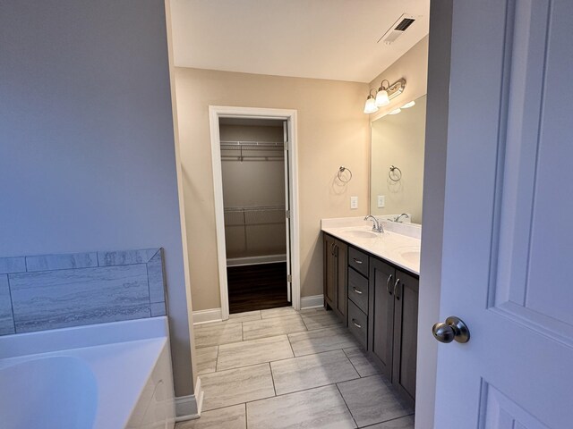 bathroom featuring tiled bath and vanity