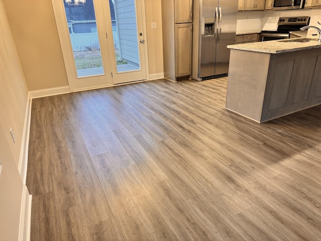 kitchen featuring sink, light hardwood / wood-style flooring, appliances with stainless steel finishes, light stone counters, and kitchen peninsula